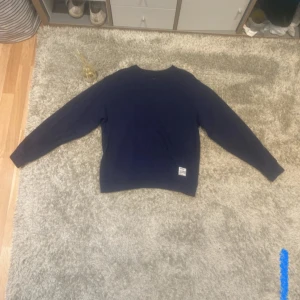 Mörkblå sweatshirt replay - Säljer en stilren mörkblå sweatshirt med tryck på ryggen. Tröjan har långa ärmar och en liten etikett vid nederkanten. Perfekt för en avslappnad look. Pris är ej hugget i sten!!!