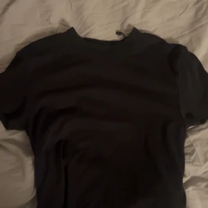 Svart t-shirt  - Säljer en klassisk svart t-shirt i storlek M. Perfekt basplagg med korta ärmar och rund hals. Passar till alla tillfällen och är lätt att matcha med andra kläder.