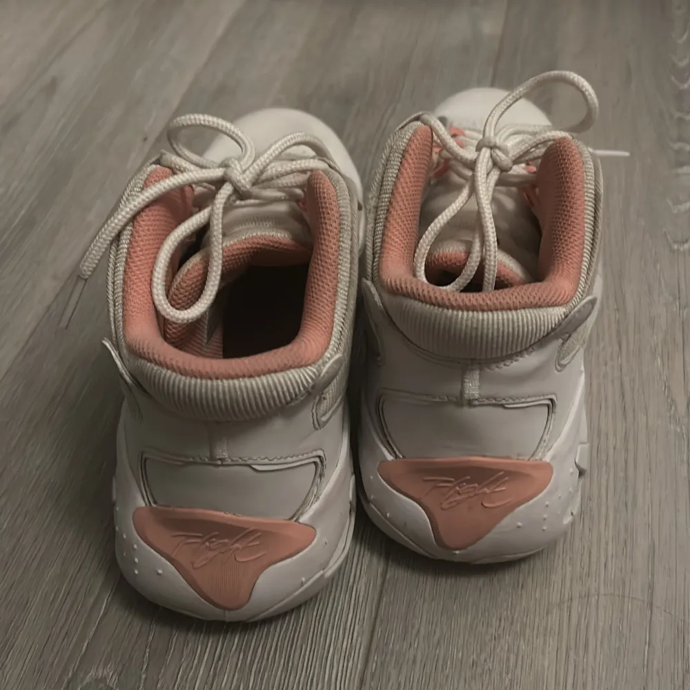 Snygga vita och rosa sneakers från Jordan med snörning och en stilren design. Skorna har en mjuk rosa insida och en vit yttersula med rosa detaljer. Perfekta för en sportig look.. Kengät.