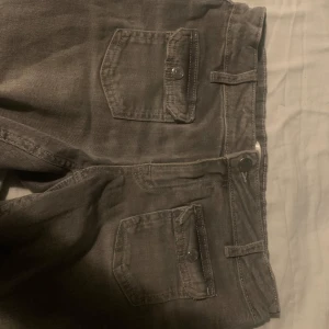 Grå jeansshorts - Skitsnygga gråa jeans med små fickor där fram. Jeansen är också lågmidjade och bootcut, har inga slitningar och används ett fåtal gånger. Innebenslängd: 80 cm, midja rakt över: 35cm. Skriv för fler bilder