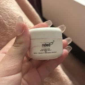Acrylic Powder från Nded - Säljer en burk med akrylpulver från Nded, perfekt för nagelförlängning och nageldesign. Burken är vit med säkerhets- och återvinningssymboler. Har en ljuslila färg lite använd