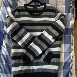 Randig kashmirtröja från John Lewis - Säljer en lyxig och mjuk randig tröja i 100% kashmir från John Lewis. Tröjan har svarta och grå ränder och långa ärmar. Perfekt för kyliga dagar.