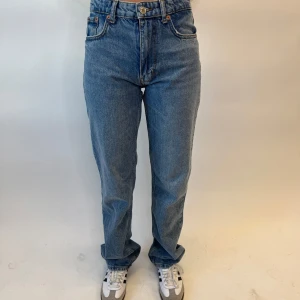 Blå jeans med hög midja - Snygga blå jeans med mid waist och klassisk femficksdesign. De har en straight passform som ger en tidlös look. Perfekta för en avslappnad stil. Som referens är modellen 164cm lång. 