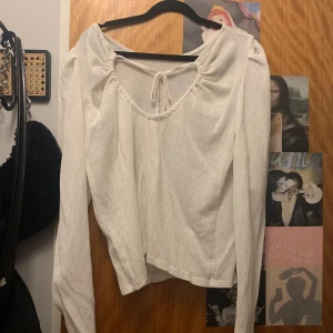 Vit långärmad topp från Lindex - Säljer en vit långärmad topp från Lindex med knytning baktill. Toppen har en lös passform och är tillverkad i ett mjukt material. Perfekt för en avslappnad stil.