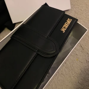 Svart väska från Jacquemus - Elegant svart plånbok från Jacquemus i skinn med guldfärgad logotyp. Oanvänd 