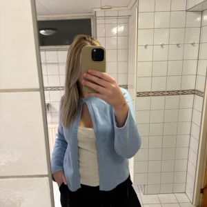 Ljusblå kofta - Säljer en ljusblå kofta med långärmad design. Perfekt för en avslappnad stil och kan enkelt matchas med olika toppar. Koftan har en enkel och stilren look.