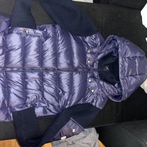 Moncler cardigan - Snygg mörkblå helt sprillans ny moncler cardigan med stickade ärmar och huva. Jackan har dragkedja och knappar framtill för extra stil och funktionalitet. Perfekt för kyliga dagar. Skit snygg och perfekt nu till vintern. Fick den som en tidig julklapp av min farsa dock inget kvitto. Säljer den eftersom att den är lite liten. Pris kan diskuteras vid snabb affär!