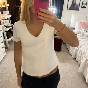 Vit v-ringad t-shirt från Zoul - Säljer en stilren vit t-shirt från Zoul med v-ringning. Perfekt basplagg för alla tillfällen. Kortärmad och i mjukt material för en bekväm passform.