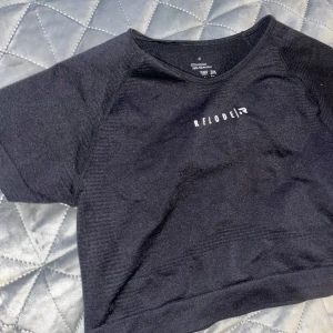 Svart kortärmad topp från RELODE  - Snygg svart topp från ReLoad med korta ärmar och en stilren design. Perfekt för en avslappnad look eller träning. Tillverkad i ett mjukt och bekvämt material.