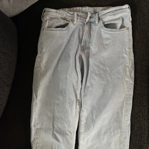 Ljusblå jeansbyxor - Säljer ett par ljusblå jeansbyxor med klassisk femficksdesign och knappgylf. Perfekta för en avslappnad stil. Passar bra till både sneakers och kängor.