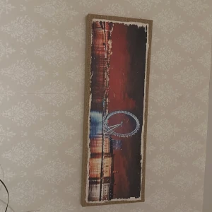 Tavla med motiv av pariserhjul - Snygg tavla med ett motiv av ett upplyst pariserhjul mot en röd kvällshimmel. Tavlan har en rektangulär form och är inramad med en ljus ram. Perfekt för att ge rummet en modern och urban känsla.