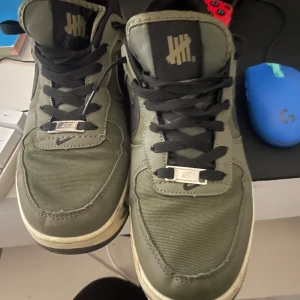 Nike Air Force i olivgrön ballistic sp - Säljer ett par olivgröna Nike Air Force med svart snörning och detaljer. Skorna har en klassisk design med märkets logga på plösen och en robust sula.