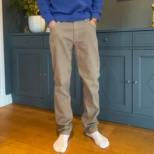 Beige byxor från Hansen & Jacob - Snygga beige byxor från Hansen & Jacob med normal passform. Byxorna har en klassisk design med knappar och dragkedja. Perfekta för en stilren look.