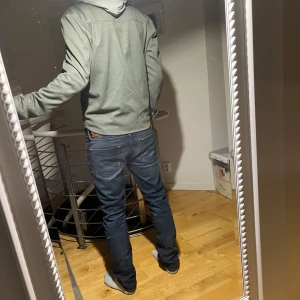 Grön overshirt - Säljer en stilren grön overshirt med dragkedja. Perfekt för en avslappnad look. Den har långa ärmar och en praktisk ficka framtill.