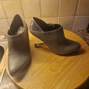 Grå klackskor med spetsig tå.  Svart/grå - Snygga grå klackskor med spetsig tå och unik klackdesign. Perfekta för att ge en stilren touch till din outfit. Märkte UNITED NUDE. Använd 2ggr.ord pris 3000kr 