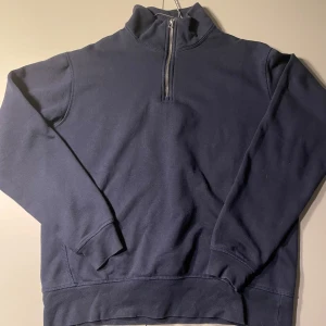 Mörkblå tröja med dragkedja från Zara - Säljer en mörkblå tröja från Zara med halv dragkedja och hög krage. Perfekt för kyliga dagar med sin bekväma passform och långa ärmar.