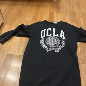 Svart långärmad tröja från H&M Divided med UCLA-tryck - Säljer en svart långärmad tröja från H&M Divided med ett stort vitt UCLA-tryck på framsidan. Tröjan har en rund halsringning och är perfekt för en avslappnad stil. Passar bra till jeans eller leggings.