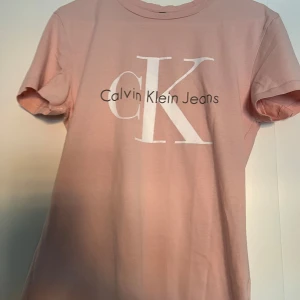Rosa t-shirt från Calvin Klein Jeans - Snygg rosa t-shirt från Calvin Klein Jeans med stort CK-logotyptryck på framsidan. Perfekt för en avslappnad stil. Tillverkad i mjukt material för extra komfort.