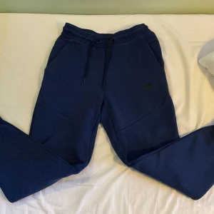 Blå mjukisbyxor från Nike - Säljer ett par bekväma blå mjukisbyxor från Nike. Byxorna har en elastisk midja med snörning och praktiska fickor. Perfekta för en avslappnad stil.