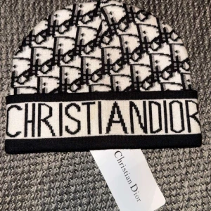 Christian Dior mössa - Snygg svartvit mössa från Christian Dior med ett ikoniskt mönster och logotyp. Perfekt för att hålla stilen under kallare dagar.obs:skriv innan köp