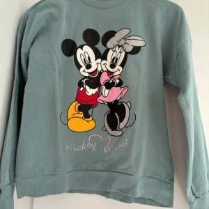 Grå Disney-tröja med Musse och Mimmi - Superfin grå tröja från Disney med ett stort tryck av Musse och Mimmi på framsidan. Perfekt för alla Disney-fans! Tröjan är långärmad och har en bekväm passform. Perfekt för höst och vintermys! 🐭❤️ Köparen betalar frakt. 
