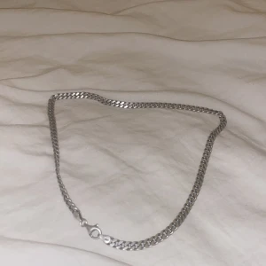 Silverfärgat halsband - Snyggt och stilrent silverfärgat halsband med en klassisk kedjedesign. Perfekt för både vardag och fest. Halsbandet har en enkel låsmekanism som gör det lätt att ta på och av. Passar perfekt till alla outfits och ger en elegant touch. Nypris 1400 kr, 100% äkta. Kvitto finns
