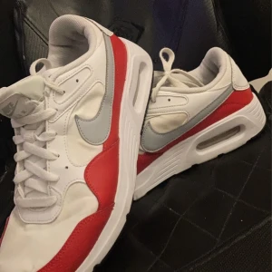 Nike Air Max i vitt och rött - Säljer ett par snygga Nike Air Max i vitt och rött. Skorna har en klassisk design med synlig Air-dämpning i sulan för extra komfort. De är i mycket bra skick och perfekta för både vardag och träning. Storlek herr 44.
