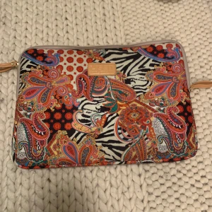 Färgglad datorväska från LISEN - Säljer en supercool datorväska från LISEN. Väskan har en dragkedja och är perfekt för att skydda din laptop med stil. Färgerna är en mix av rött, orange, blått och svart, vilket gör den till en riktig färgklick. Perfekt för att liva upp vardagen!