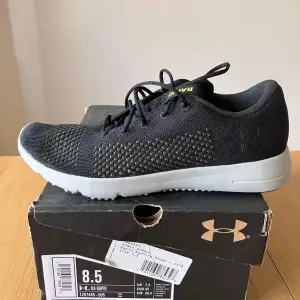 Säljer ett par snygga svarta sneakers från Under Armour i storlek 42. De har en stilren design med vita sulor och diskreta gröna detaljer. Perfekta för träning eller vardagsbruk. Skorna är i mycket bra skick och har bekväm passform med snörning för optimal passning.