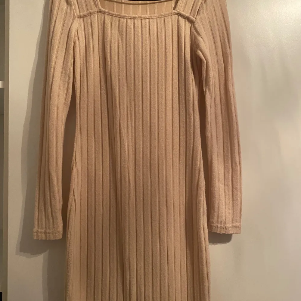 Säljer en superfin beige ribbad klänning i mycket bra skick. Den har långa ärmar och en stilren design som passar perfekt för höst och vår. Klänningen är i ett mjukt och bekvämt material, perfekt för både vardag och festliga tillfällen.. Klänningar.