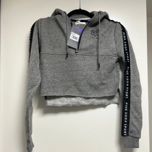 Kort hoodie med prislapp - Kort oanvänd hoodie i storlek XS. Säljes pga används ej. Prislapp kvar! Pris 250kr 