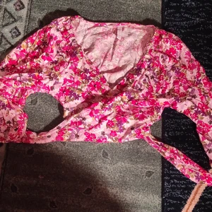 Blommig rosa sommar top - Säljer en superfin blommig top i rosa och vita nyanser. Perfekt för sommaren med sitt fina material. Tröjan har en v-ringad design och korta ärmar, vilket gör den idealisk för varma dagar. Man knyter den vid magen. Passar perfekt till både vardag och fest! 🌸
