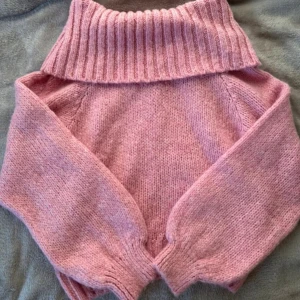 Rosa stickad Off shoulder från Gina Tricot - Mysig rosa stickad tröja från Gina Tricot med en bred ribbad krage. Perfekt för kyliga dagar med sin mjuka och varma känsla. Tröjan har långa ärmar och ribbade detaljer vid ärmslut och nederkant.🩷