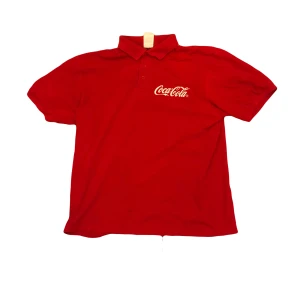Röd Coca-Cola t-shirt - Snygg röd t-shirt från Coca-Cola med klassisk logga på bröstet. Baksidan har texten 'Ein Team - Ein Ziel!' och årtalen '54, '74, '90, 2014. Perfekt för dig som älskar retro och sportig stil.                                                     Storlek:L Längd:66 cm Midjeöppning:58 cm Ermöppning:16 cm 