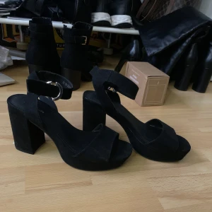 Svarta klackskor med spänne - Snygga svarta klackskor från Din Sko med block klack och justerbart silvrigt spänne runt ankeln. Tillverkade i mocka för en elegant look. Har använt 1 gång på bal, väldigt bekväma då jag hade de hela kvällen. Perfekta för finare tillfällen så som till balen, studenten eller skolavslutning.