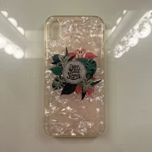 Transparent mobilskal med flamingo och text - Snyggt transparent mobilskal med ett unikt mönster av flamingos och gröna blad. Texten 'Enjoy every moment summer' är tryckt i mitten med glittriga detaljer. Perfekt för att ge din mobil en somrig och stilren look. Passar iphone XR.