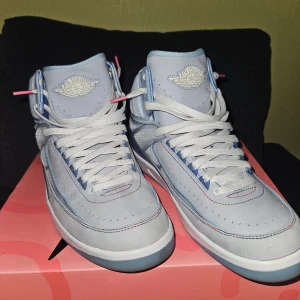 Nike Air Jordan x j.balvin  - Snygga Nike Air Jordans i ljusblått med vita snören och unika lysande detaljer på plösen. Skorna har en klassisk hög design med perforeringar för extra stil och komfort.