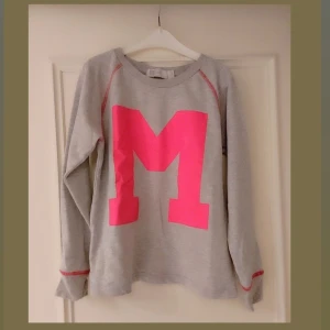 Grå sweatshirt med rosa M,storlek 140,10 år - Säljer en grå sweatshirt med ett stort rosa M på framsidan. Tröjan har långa ärmar och rosa detaljer vid ärmsluten. Perfekt för en avslappnad stil.Det är en tröja till flickor och storlek är 140, 10 år.
