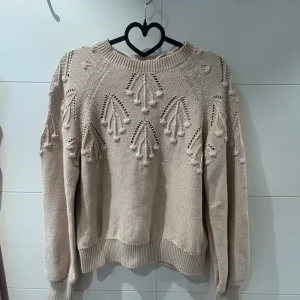 Beige stickad tröja från Freequent - Säljer en beige stickad tröja från Freequent med ett vackert hålmönster framtill. Tröjan har långa ärmar och ribbade muddar vid ärmslut och nederkant. Tröjan är använd en gång💘