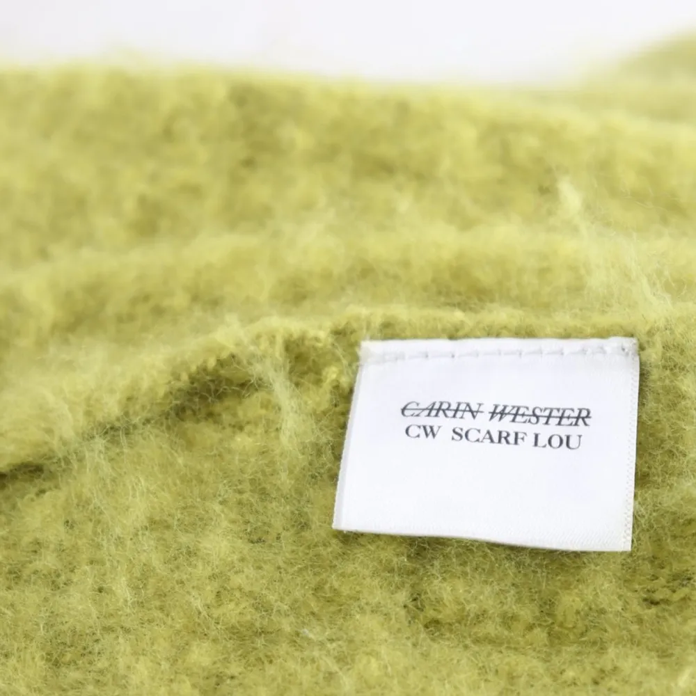 Säljer en lång och mysig grön halsduk från Carin Wester. Den är tillverkad i 100% polyester och har dekorativa fransar i ändarna. Perfekt för att hålla dig varm under kyliga dagar.. Muu.