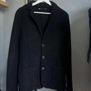 Stickad kavaj/cardigan  - Snygg svart kavaj/cardigan från WE i storlek M sitter som S. Den har en klassisk design med knappar framtill och långa ärmar. Perfekt för en stilren look. Skick 8/10.