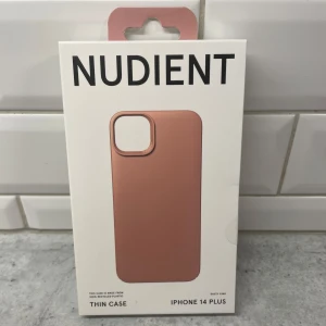 iPhone 14 plus mobilskal  - Helt oanvänt mobilskal från märket Nudient i färgen ”dusty pink”. Gjord för Iphone 14 plus.  Nypris på deras officiella hemsida ca 350kr.  Information - 100% återvunnen plast - Ultratunn design (1mm) - Mjukt premium mikrofiberinlägg - Kompatibel med trådlös laddning - Designad av Jesper Ståhl  Förpackning aldrig öppnad så precis som från butik 10/10 skick.  Pris kan diskuteras vid snabb affär!