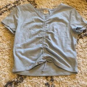 Ljusblå ribbad topp - Säljer en ljusblå ribbad topp från Lindex med korta ärmar och v-ringning. Storlek 146/152🩷🩷