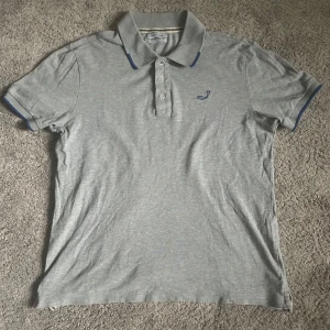 Grå pikétröja från Jacob Cohen - Säljer en stilren grå pikétröja från Jacob Cohen. Tröjan har en klassisk krage med blå detaljer och tre knappar framtill. Perfekt för en avslappnad men ändå snygg look. Helt oanvänd, Skick 10/10✅. Skriv vid minsta fundering kring nånting👍