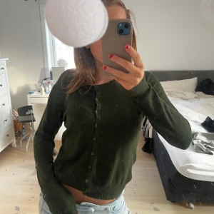 Mörkgrön kofta - Säljer en stilren mörkgrön kofta med knappar framtill. Koftan har långa ärmar och en normal passform, perfekt för kyligare dagar. Passar bra till både jeans och kjol.