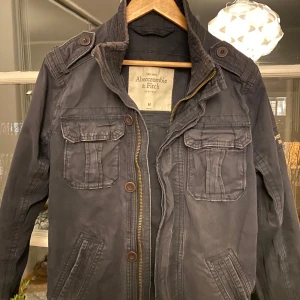 Field Jacket från Abercrombie & Fitch - Säljer denna goa Field jacket/Overshirt/Army jacket från Abercrombie & Fitch! Riktigt snygg, lätt att matcha med allt! Materialet är lite ”hårt” vilket är sjukt gött till vårjackor. Skicket är bra, kan anmärka på att vissa delar är skrynkliga och att kanterna är lite solblekta (Därav priset) men enligt mig gör det bara jackan fetare! Annars inga märkbara defekter👍 Skriv om ni har frågor eller prisförslag! 