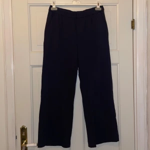 Mjukis/kostymbyxor  - Marinblåa byxor i skönt stretchigt material, hög midja och vida ben. Perfekta för en stilren look. Två fickor fram och två fejk bak. 
