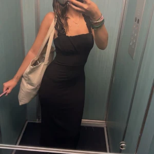 Svart långklänning - Snygg svart långklänning med smala axelband och en elegant passform. Perfekt för en stilren look. Klänningen har en enkel design som gör den lätt att matcha med accessoarer. 