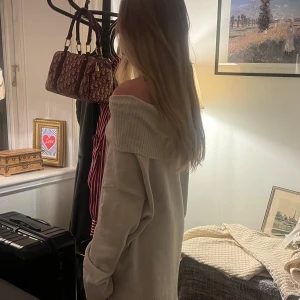 Beige offshoulder tröja - Säljer en mysig beige offshoulder tröja med långa ärmar. Perfekt för en avslappnad stil och kan stylas på olika sätt. Tröjan har en bred ribbad kant vid axlarna som ger en snygg detalj.