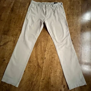 Beige chinos från Polo Ralph Lauren - Snygga beige chinos från Polo Ralph Lauren i slim fit. Byxorna har en klassisk design med knappstängning och fickor bak. Perfekta för en snygg look.